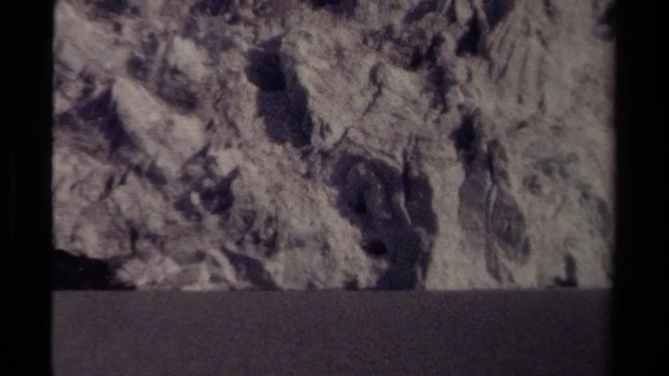 1979 8mm British Columbia footage showing pale icy cliff textures above a dark water or valley band, with film-frame borders visible.