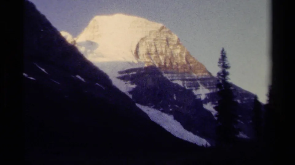 Exposure shifts to a paler 8mm view of the snowy British Columbia mountain, with conifers and dark slopes in the foreground.