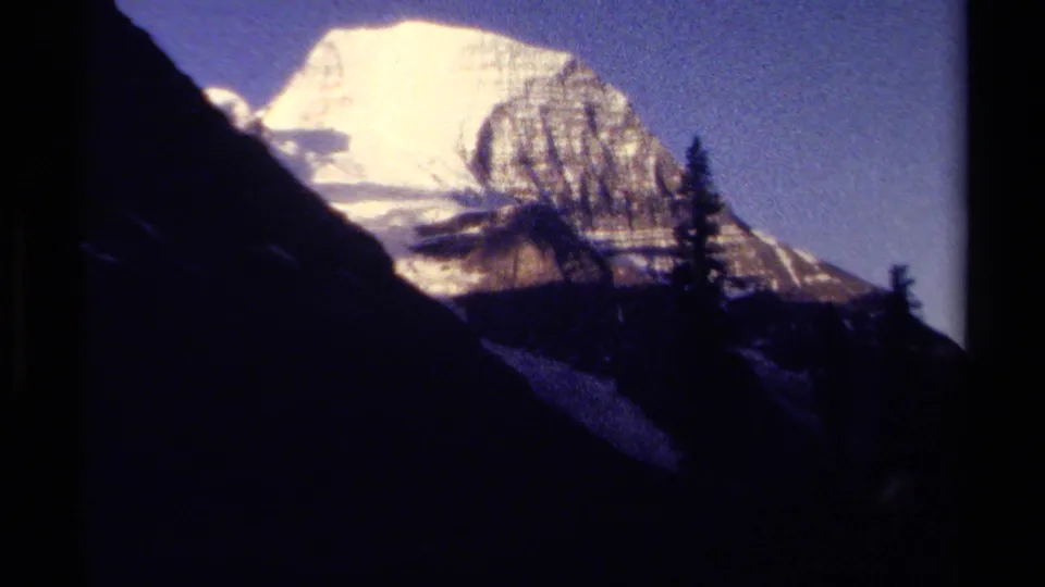 The 1979 8mm shot ends on a bright snowy mountain peak in British Columbia, partly framed by dark terrain and conifers.