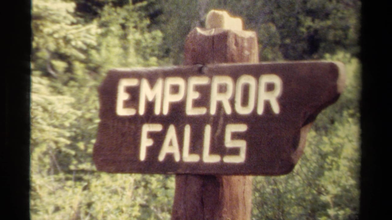 1979 8mm frame of a rustic wooden Emperor Falls sign set against dense British Columbia forest greenery.