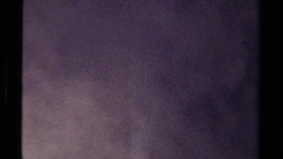 Abstract 8mm exposure frame with dark borders, purple-gray texture, and no identifiable people or location details.