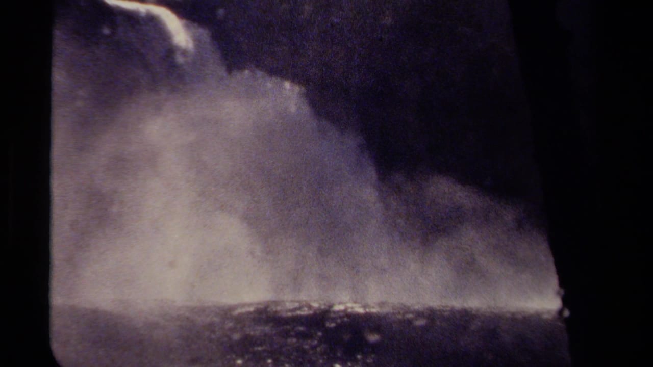1979 British Columbia home-movie frame showing a close view of a waterfall dropping through heavy mist with dark film edges.