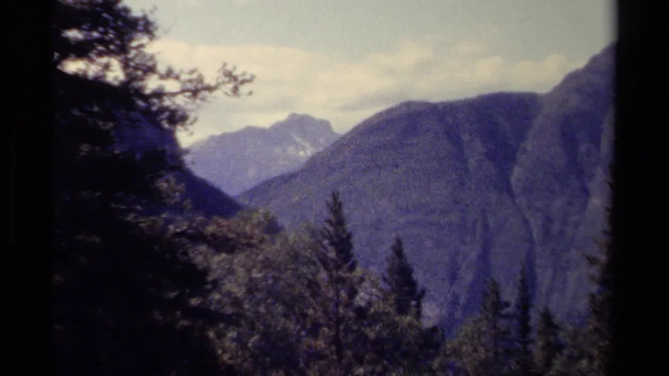 British Columbia mountain valley seen through evergreen foreground in soft, grainy 1979 8mm footage.