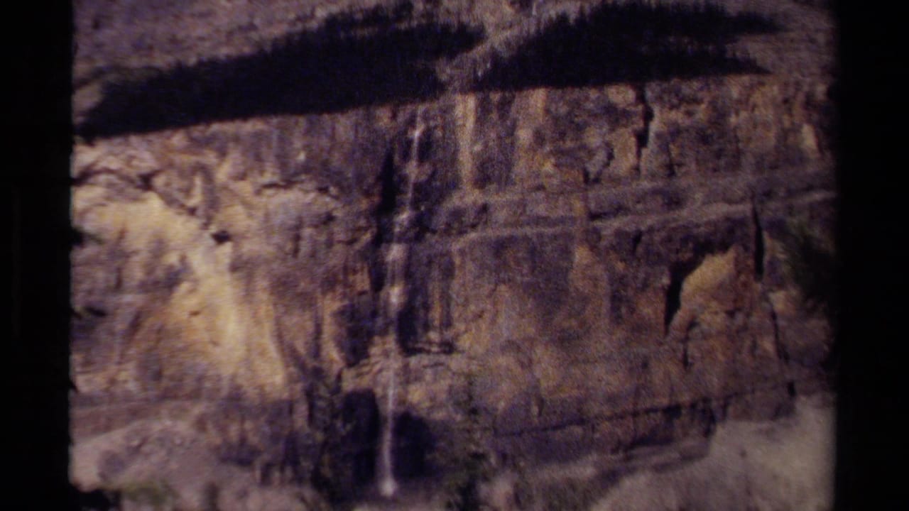 1979 British Columbia 8mm frame showing a rugged rock wall with a narrow waterfall dropping down the cliff face.