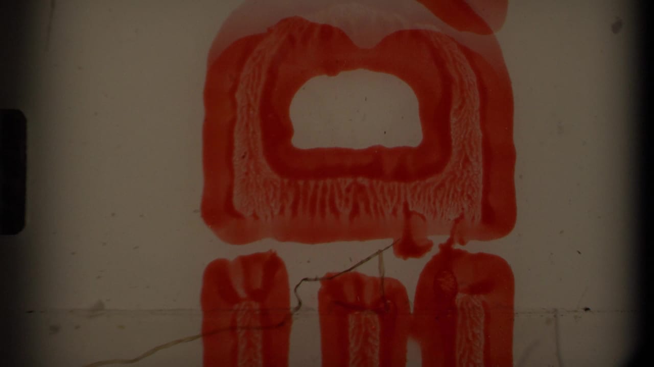 Red graphic or object on a pale background with film gate edges visible.