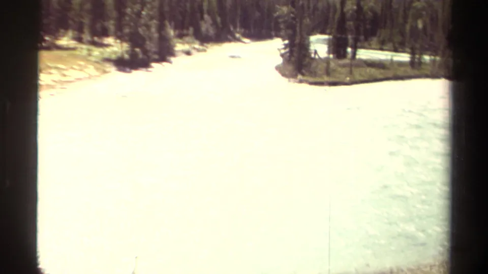 8mm home-movie view of rushing Moose River water through a snowy forested landscape in British Columbia.
