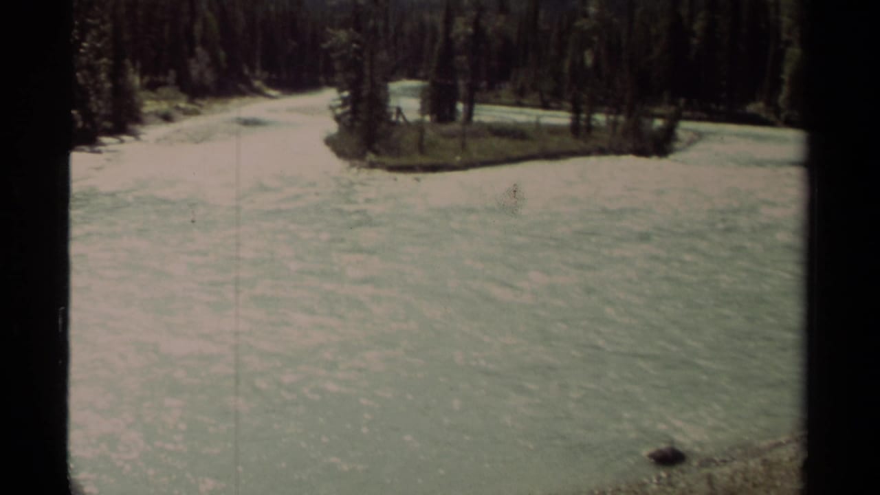 A pale river curves past evergreen forest with dark 8mm frame borders.