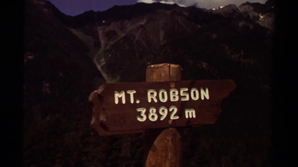 1979 British Columbia home-movie frame shows a wooden Mt. Robson 3892 m sign against rugged mountain terrain.