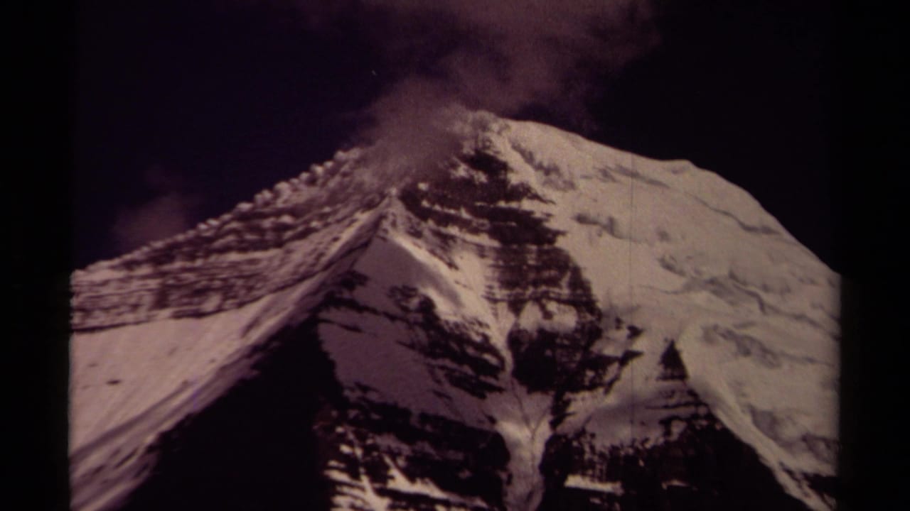 1979 British Columbia 8mm view of a snow-covered alpine peak, with dark sky and faint cloud or mist along the upper ridge.