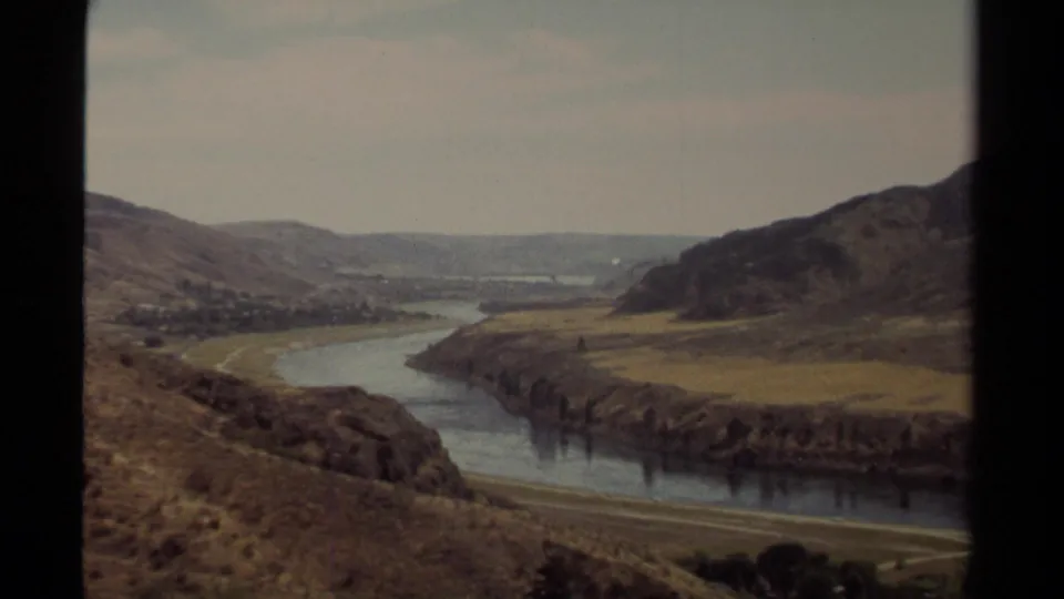 Final 1979 British Columbia 8mm frame keeps the winding river centered between dry hills, fields, and distant settlement detail.