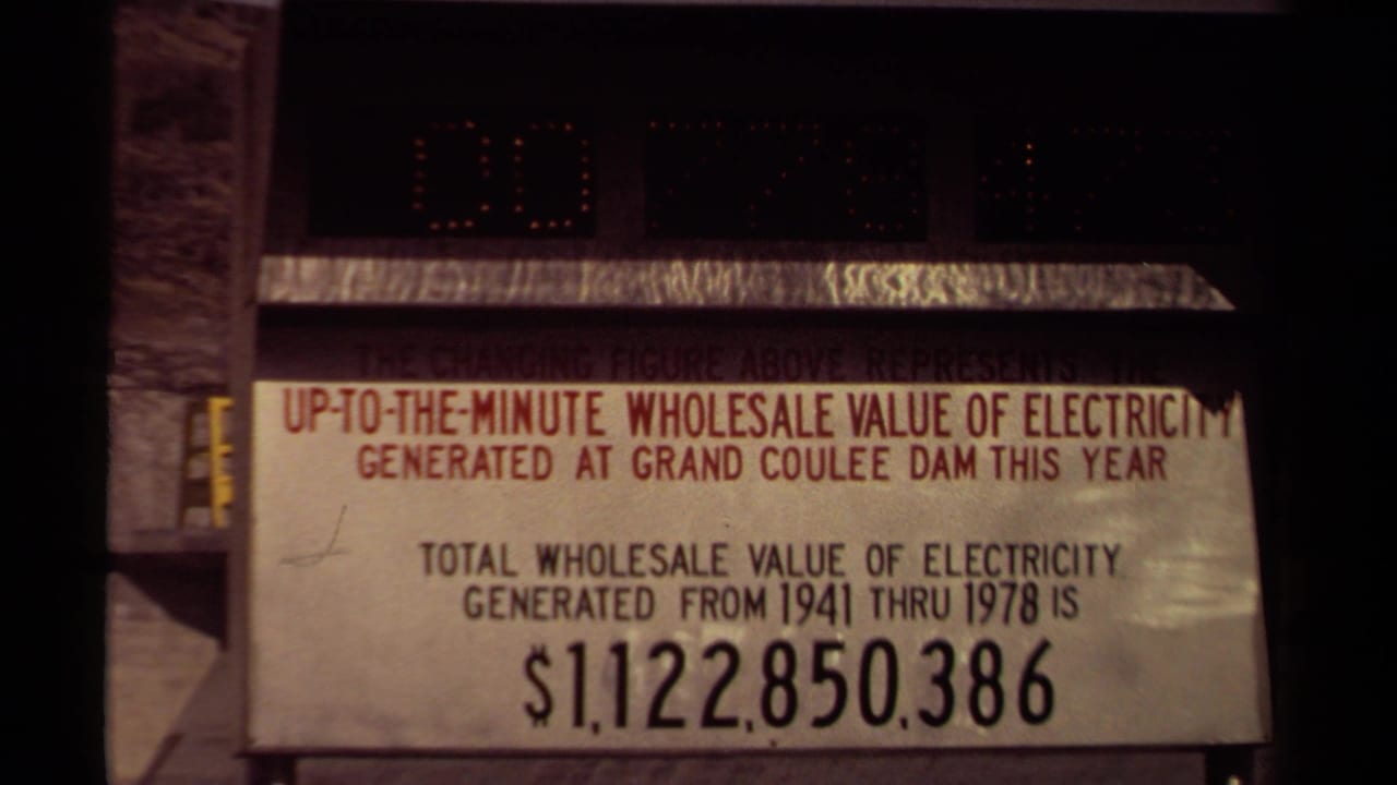 1970s 8mm frame of a Grand Coulee Dam electricity value sign with changing digits above and a printed total from 1941 through 1978.