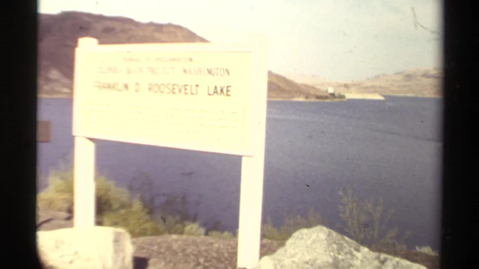 Roadside sign for Franklin D. Roosevelt Lake appears beside bright water and distant hills in the 1979 8mm footage.