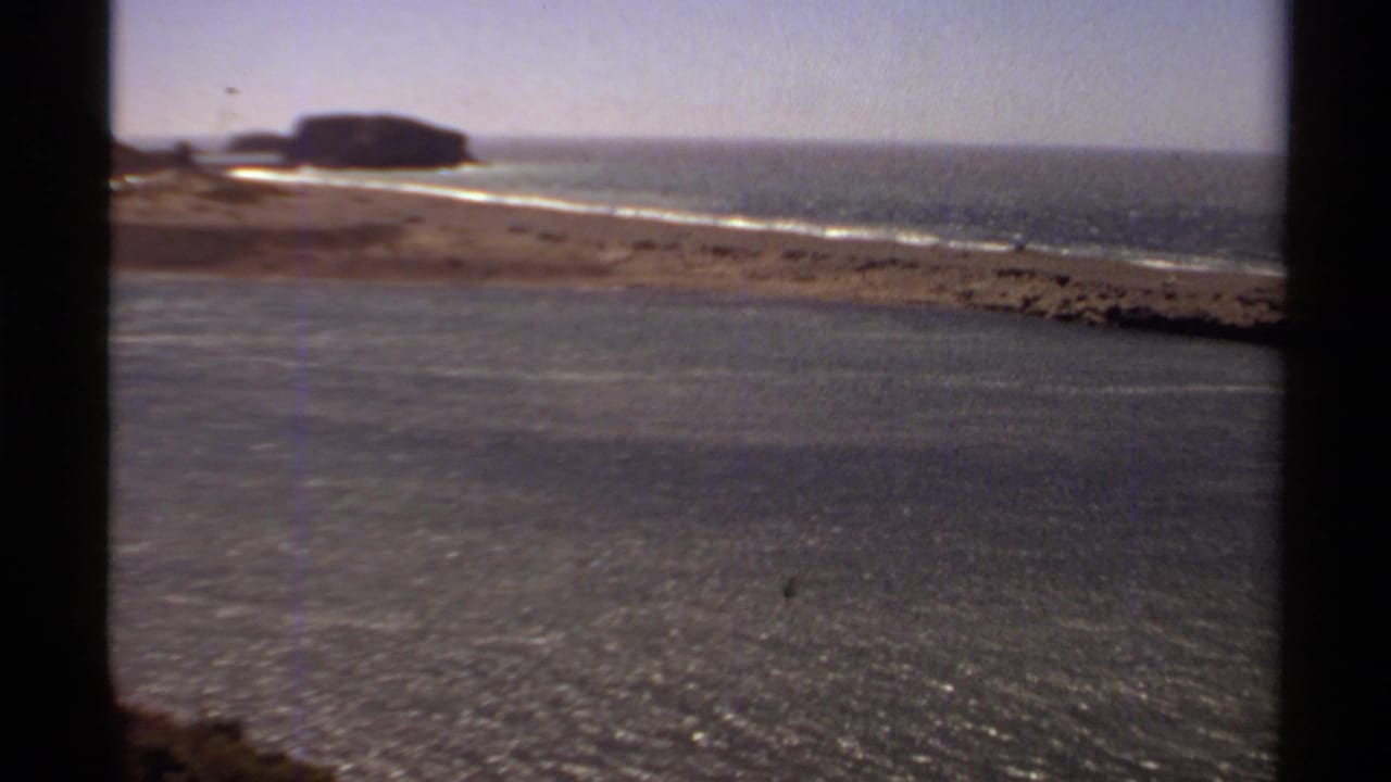 Coastal water and sandy shoreline with a rocky point in the distance.