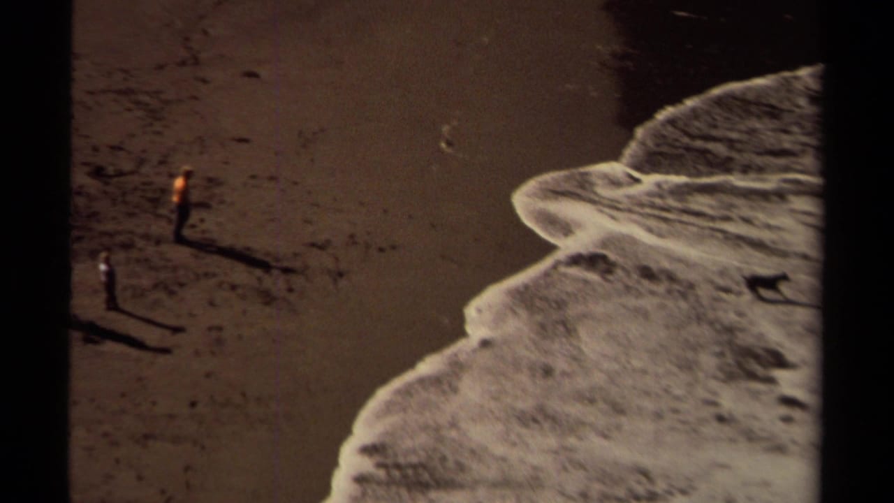 Two small people on dark beach sand beside foamy surf in a divided contact-sheet frame.