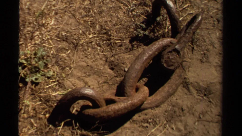 Rusted chain and weathered ground detail in supported 1980 Mendocino 8mm home-movie footage.