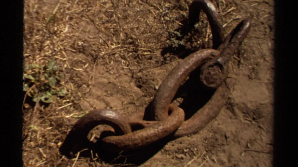 Close view of a rusty chain on dry ground in Mendocino, California, from 1980 8mm home-movie footage.