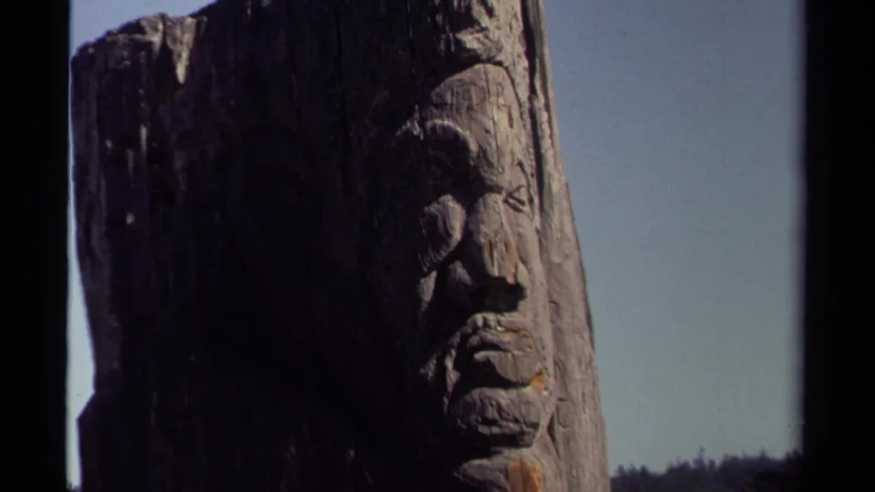 The final frame shows a tight 1980 Mendocino view of the carved wooden monument, with distant houses low in the background.
