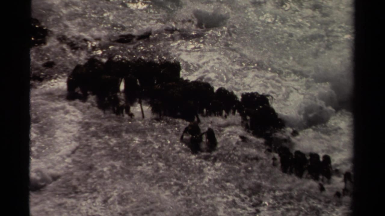 Grainy 1980 8mm view of Mendocino coastal waves striking a jagged rock formation.