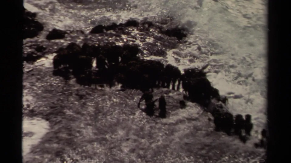 Mendocino shoreline surf rolls over dark rocks in a soft, grainy 1980 8mm frame.