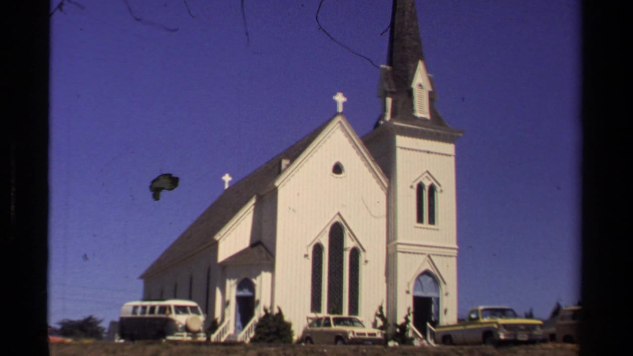 Mendocino, California church street view from 1980, with a white steepled church, dark tower, and parked period cars.