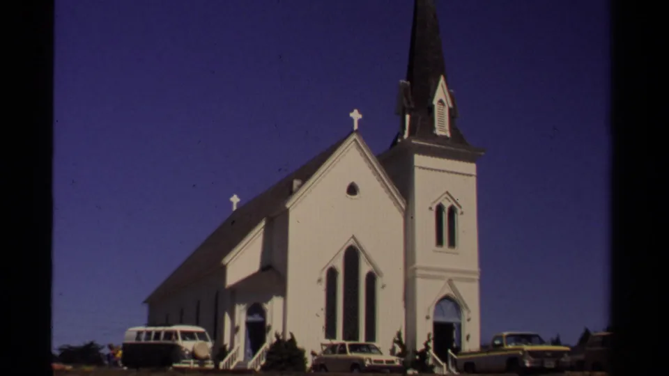 1980 Mendocino street frame showing a white church with a dark steeple and several parked cars along the curb.