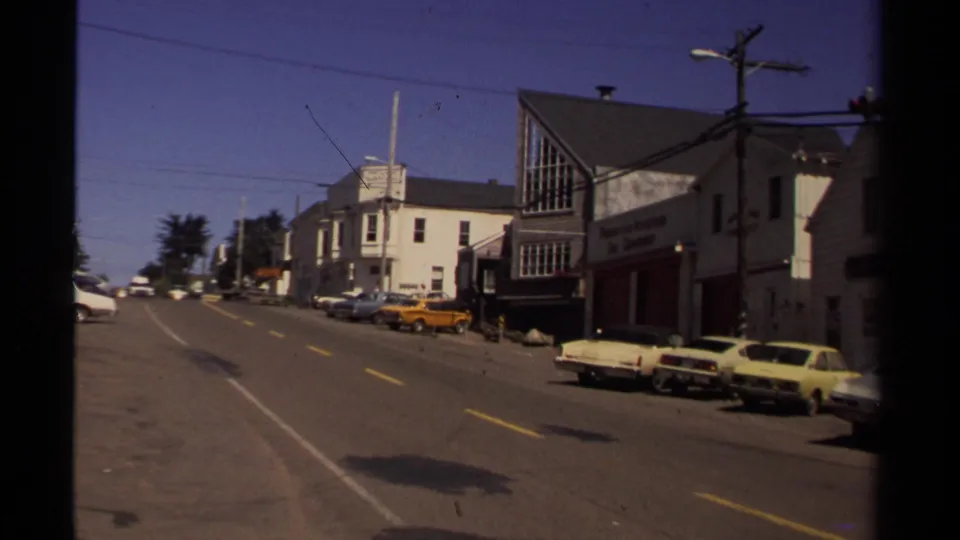 Supplied 1980 Mendocino street scene showing a row of parked classic cars, commercial storefronts, road shadows, and overhead wires.