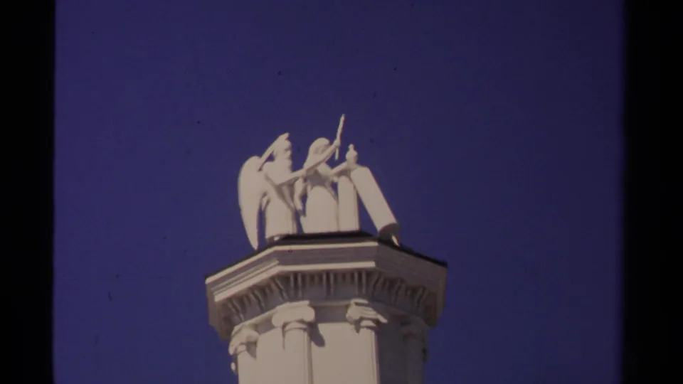 1980 Mendocino 8mm frame showing the white rooftop sculpture and ornamental column detail in a closer low-angle view.
