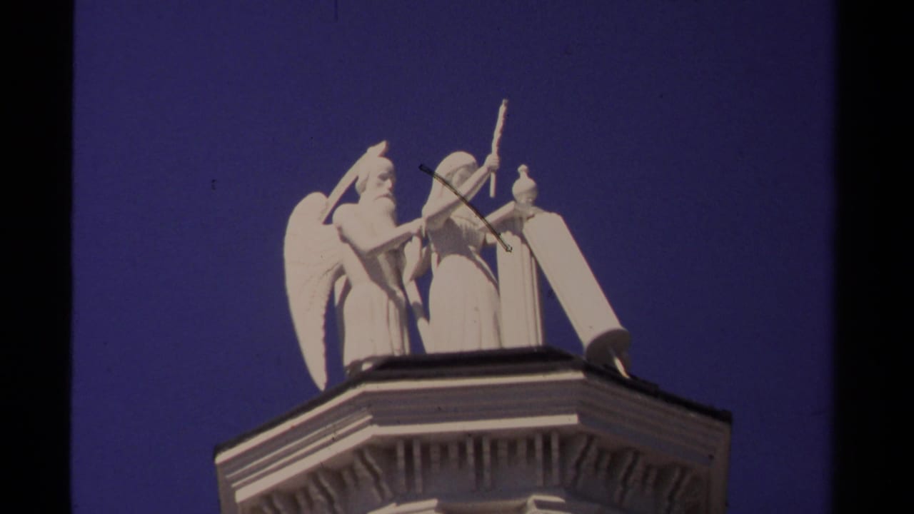 White angel sculpture on a rooftop against a deep blue sky.