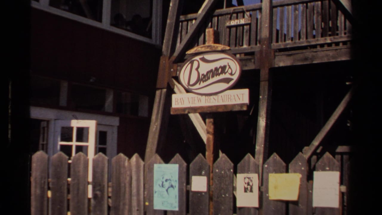 Mendocino storefront view from 1980-era 8mm footage, with Brennan's Bay View Restaurant signage, balcony railings, fence posts, and posted notices.