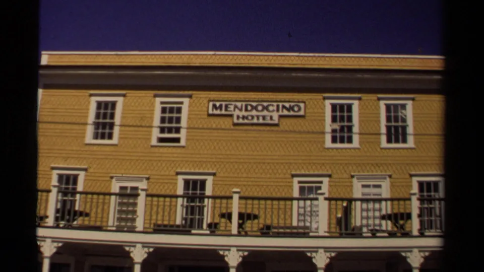 1980 Mendocino Hotel exterior with yellow siding, hotel sign, upper windows, and balcony rail along the facade.