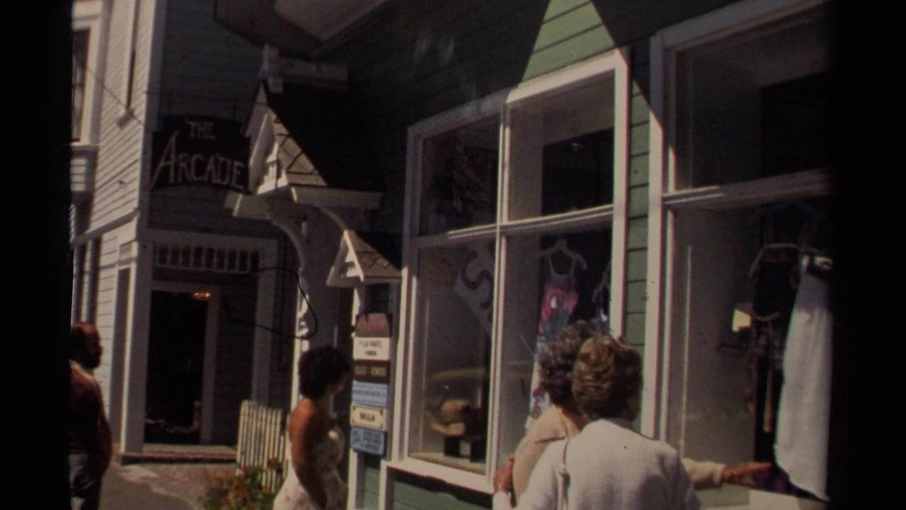 Pedestrians walk past storefronts with The Arcade sign and large shop windows.