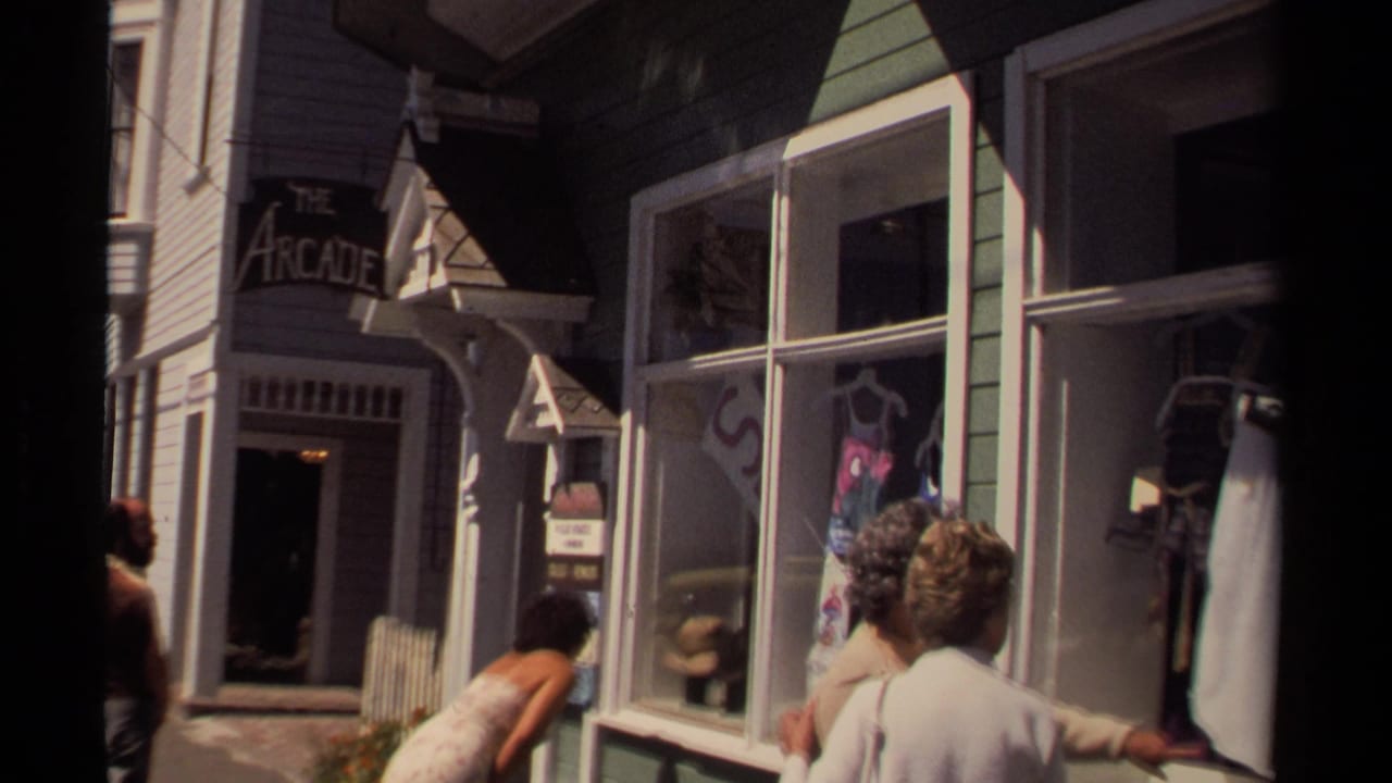 Street-level 8mm view of people passing a Mendocino storefront with display windows and The Arcade sign nearby.