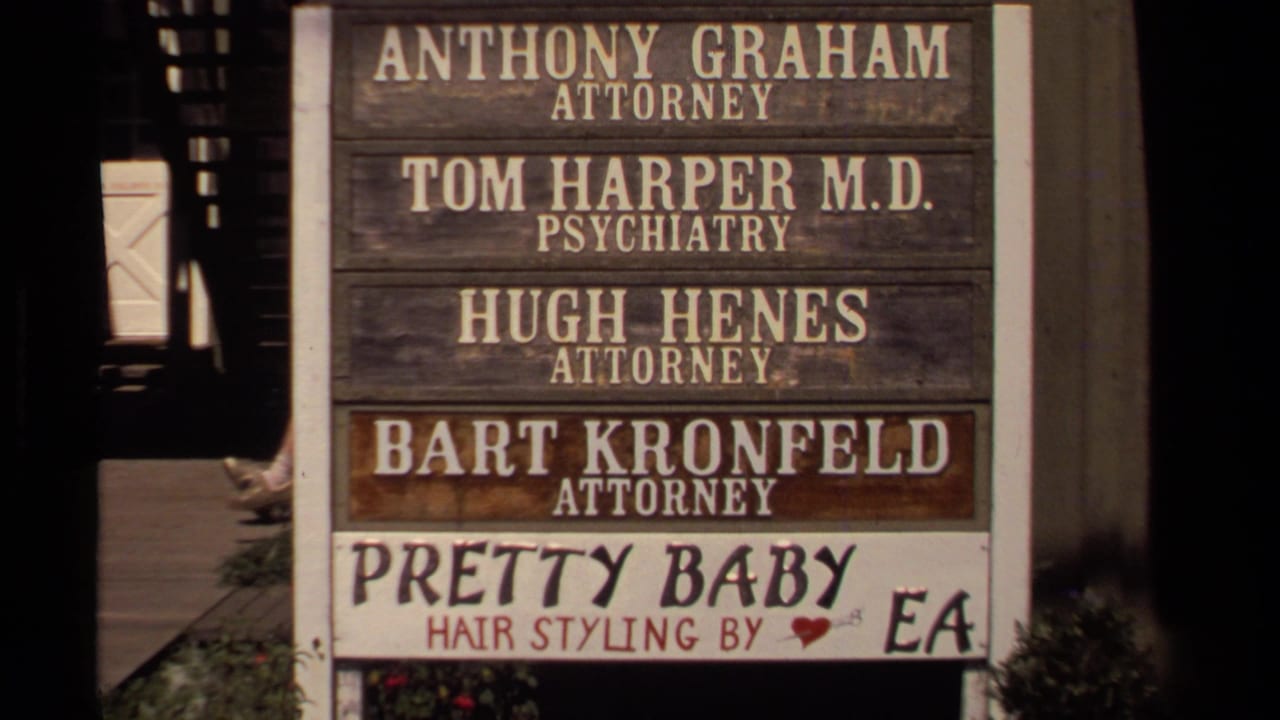 Close view of a Mendocino business directory with attorney, psychiatry, and hair-styling signage visible in 1980 home-movie footage.