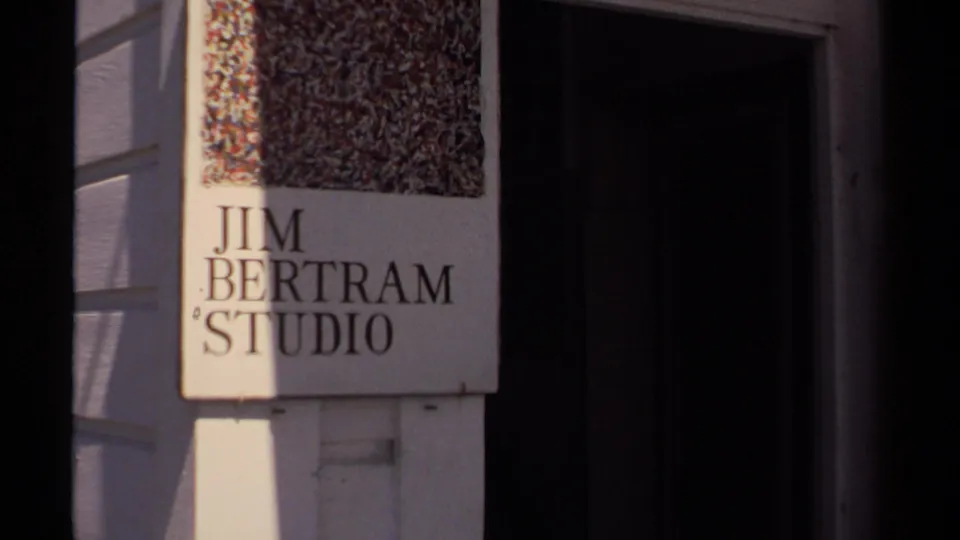 Mendocino 1980 home-movie frame showing a Jim Bertram Studio sign near a doorway on a small commercial building.