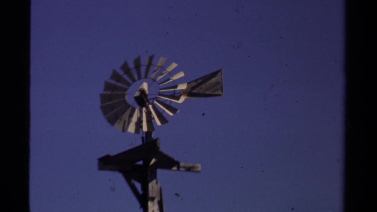Metal windmill on a wooden support against a dark blue sky.