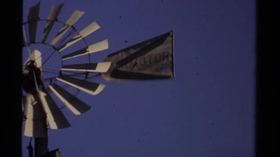 Tight home-movie frame of the windmill blades and tail vane, with weathered lettering visible in the 1980 Mendocino footage.