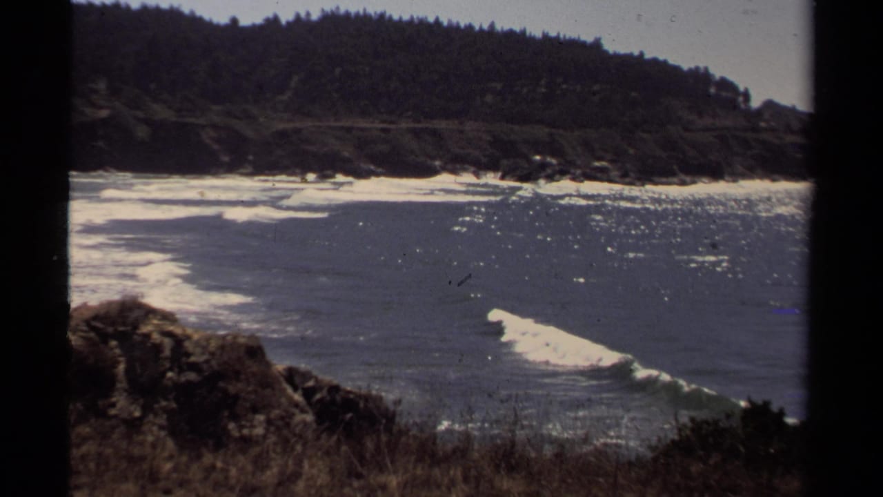 Mendocino-area coastal water and forested hills appear in a sunlit 1980 8mm home-movie frame.