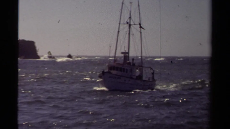 The boat marked DUTCH LADY moves across rough water near the Mendocino shoreline, with offshore rocks and surf visible.