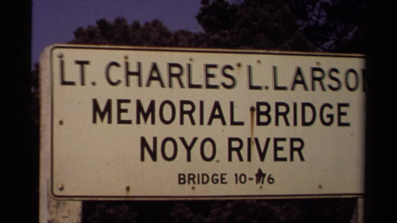 Roadside sign reading Lt. Charles L. Larson Memorial Bridge, Noyo River, with trees behind it.