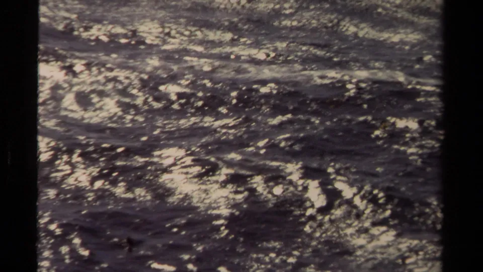 Final 8mm frame of flowing water, likely in Mendocino, with sparkling highlights, grain, and slight handheld framing.