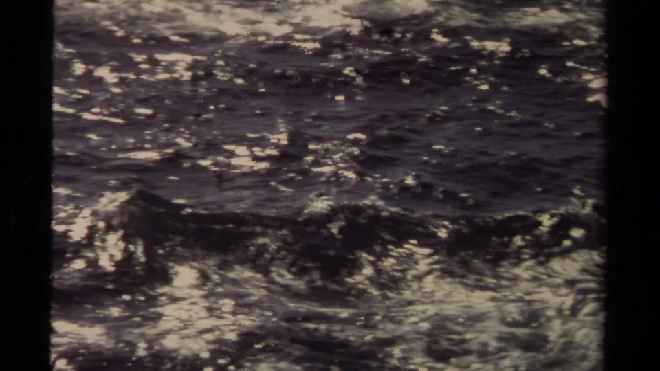Mendocino 1980 home-movie frame showing dark churning ocean water, small waves, and scattered white reflections.