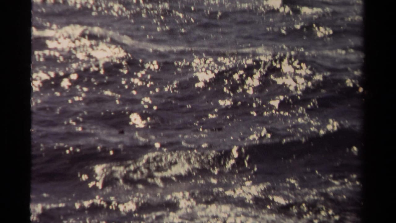 Mendocino 1980 frame with shimmering highlights over dark ocean waves and foam patches.
