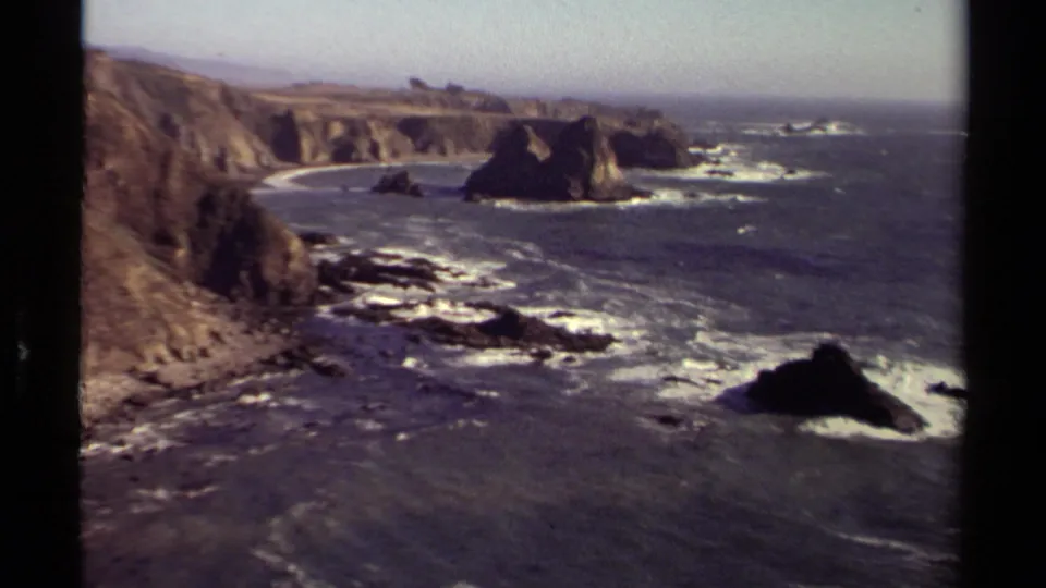 Wide 8mm view of the Mendocino, California seacoast with rocky outcrops, breaking surf, steep cliffs, and distant ocean horizon.