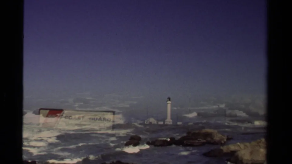 1980 8mm frame with a partial dissolve or overlap between the Coast Guard sign, Point Arena Lighthouse, and Pacific surf.