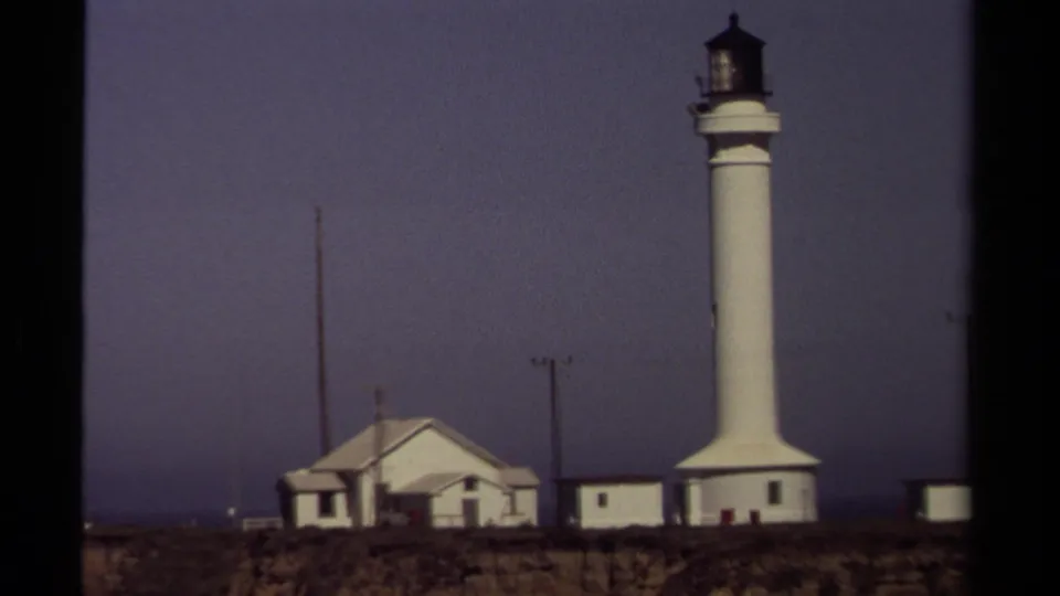 Closer 1980 home-movie view of Point Cabrillo Lighthouse, showing the white tower, lantern room, and adjacent low buildings.