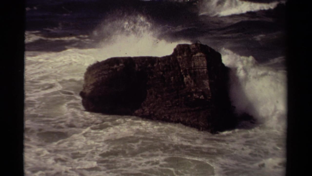 1980 8mm Mendocino coastal footage showing a dark rock formation as white surf crashes around it.