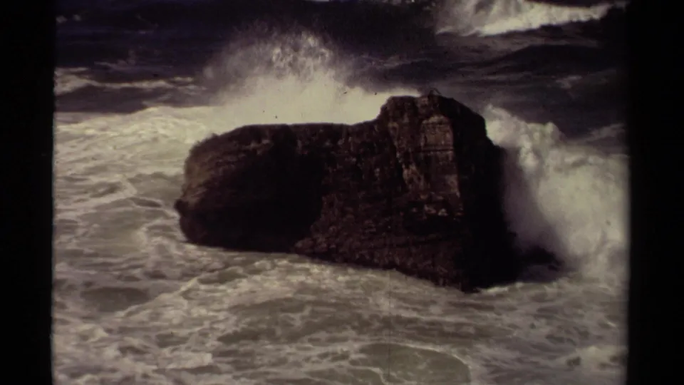 1980 8mm Mendocino coastal footage showing a dark rock formation as white surf crashes around it.