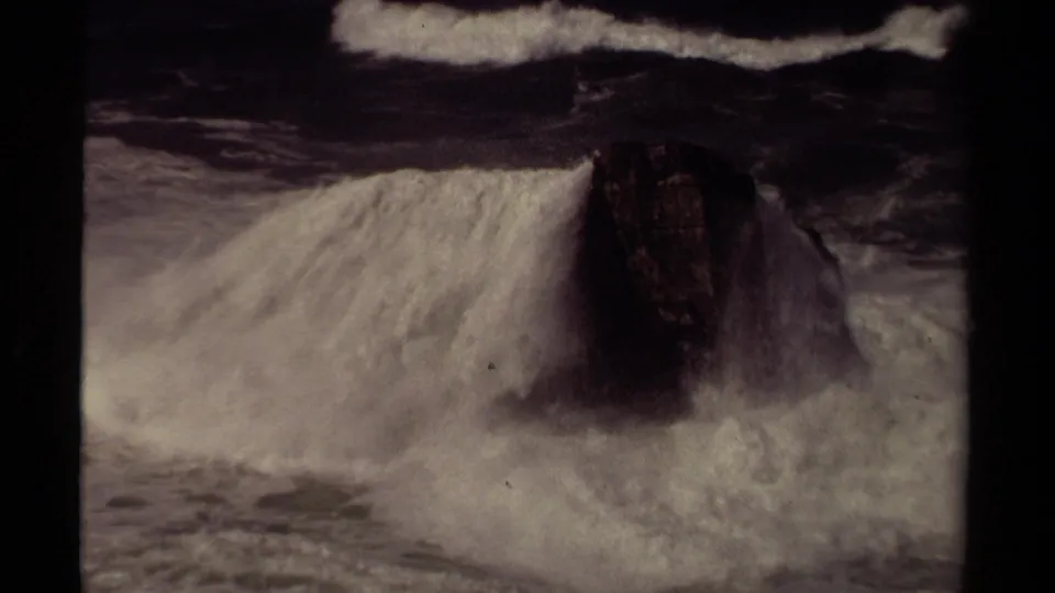 Mendocino 1980 8mm footage shows turbulent surf washing over a dark rock amid heavy foam.