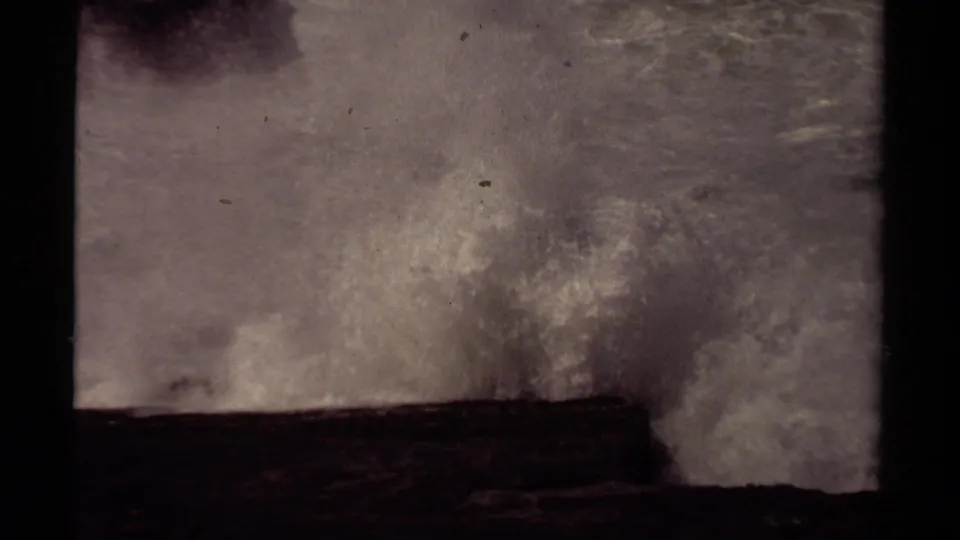 A powerful wave throws spray over a rocky Mendocino coast ledge in faded 1980 8mm footage.