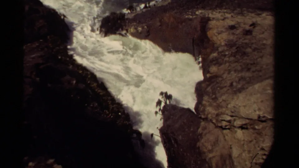 Mendocino coastal cliffs frame rushing white water, with very small human figures visible on a rocky point.